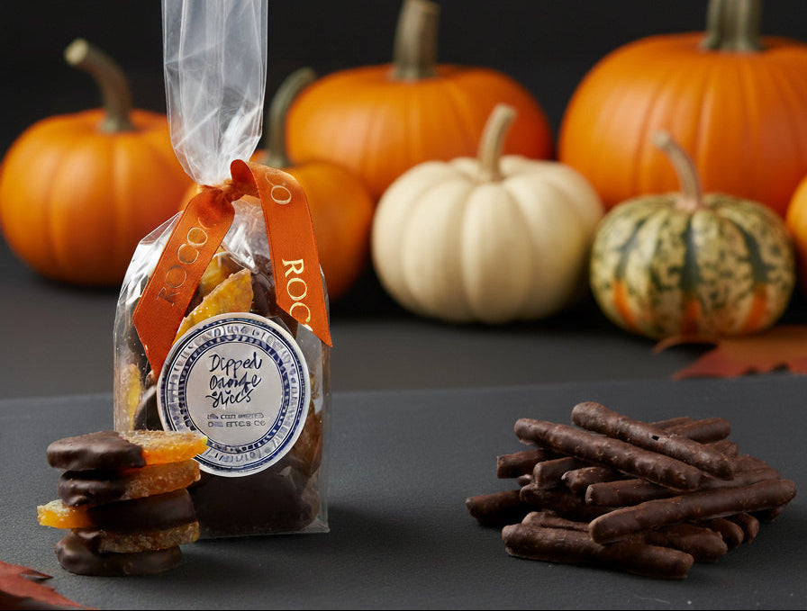 Packaged treat with pumpkins and cookies on a dark surface